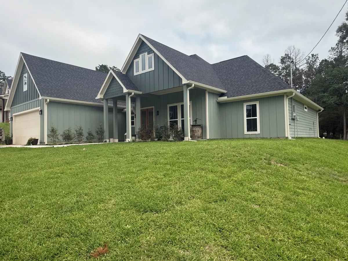 Finished home with light green board-and-batten siding, white seamless gutters, and downspouts