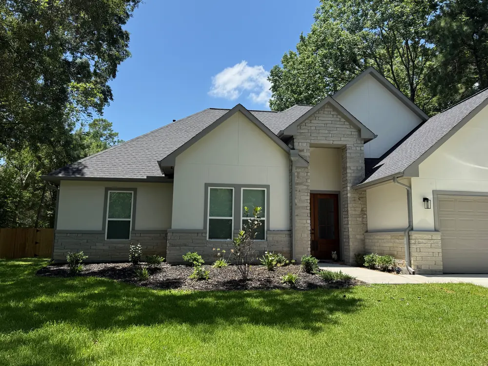 Front of a finished stucco and stone home with gray seamless gutters and downspouts